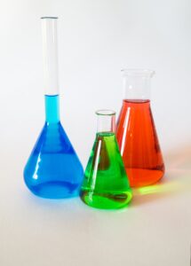 A photograph of three beakers filled with blue, green, and red liquids, respectively.